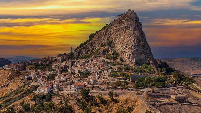 The village of Sutera clinging to Monte San Paolino in central Sicily with its houses cascading down the rocky slope above the agricultural plain